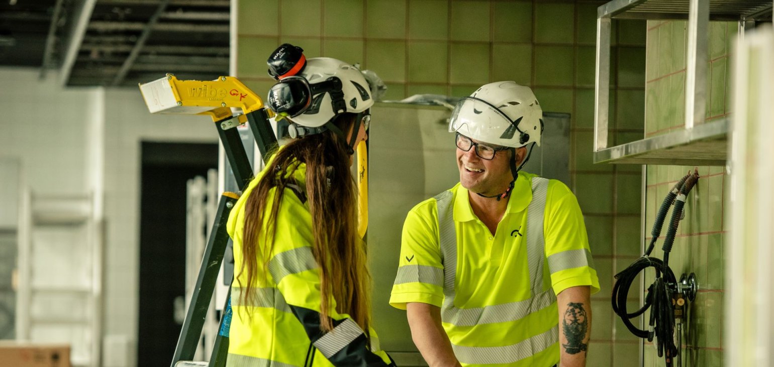 To medarbeidere i GK foran en skisse på byggeplass