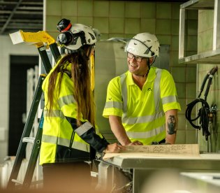 To medarbeidere i GK foran en skisse på byggeplass