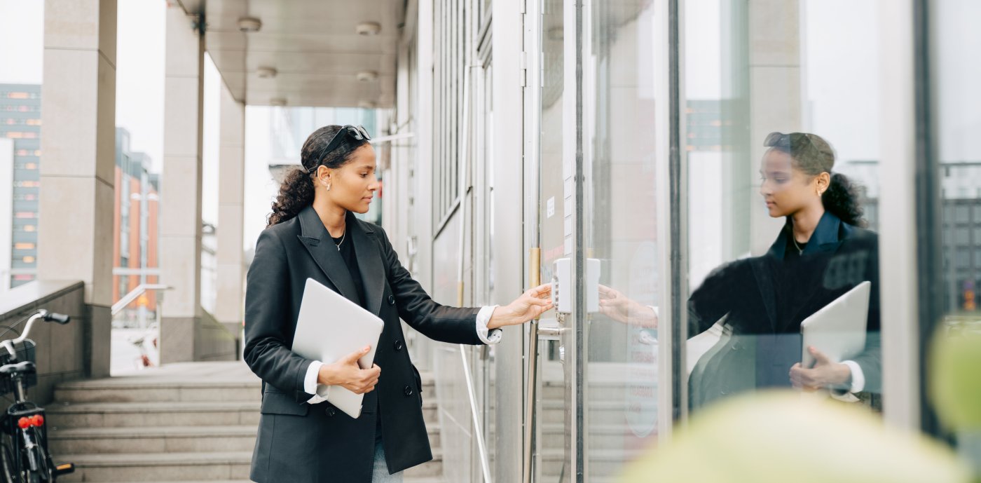 Kvinne taster inn kode på inngangsdør til kontorbygg